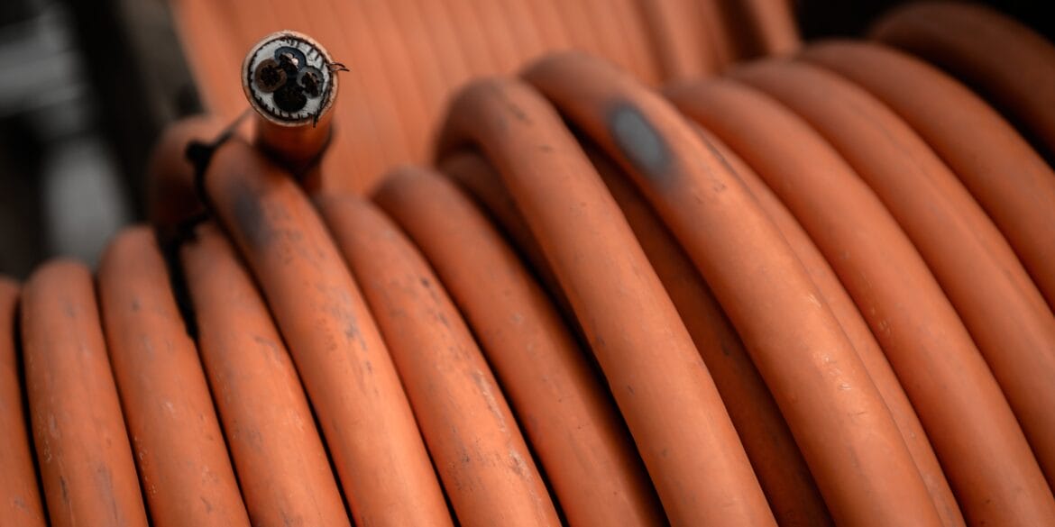 Close-up of orange industrial cables coiled together, with one frayed open end visible in the foreground.
